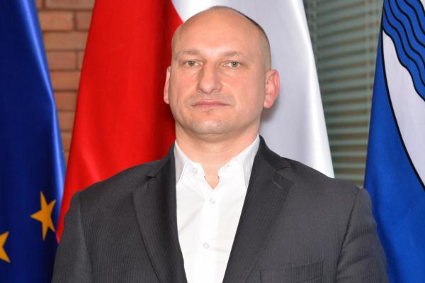 Zdjęcie portretowe mężczyzny – ubrany jest w ciemną marynarkę i białą koszulę.