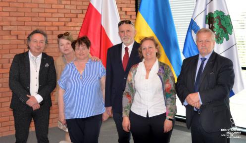 Sześć osób stojących na tle flag polskiej, ukraińskiej, unijnej oraz Konstancina-Jeziorny.
