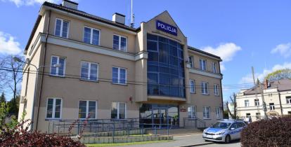 Trzykondygnacyjny budynek z jasną elewacją. Na środku w pionie znajduje się duże niebieskie przeszklenie. Na górze napis Policja w białym kolorze na niebieskim tle. Przed budynkiem stoi zaparkowany radiowóz. 