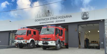 Dwa wozy strażackie, stojące przed dużym odnowionym budynkiem Ochotniczej Straży Pożarnej w Konstancinie-Jeziornie. 