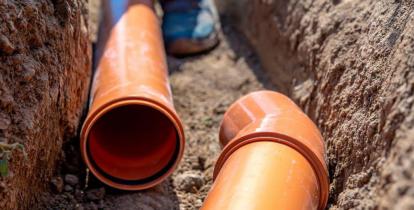 Rury kanalizacyjne (plastikowe), które są położone w tunelu wykopany w ziemi. 