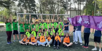 Zdjęcie grupowe około 30 dzieci, stoją w dwóch rzędach przed bramką sportową. 