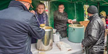 1.	Na stole stoją dwa duże garnki, mężczyzna i kobieta nakładają chochlą zupę do plastikowych talerzyków. Dwóch mężczyzn czeka na talerz.