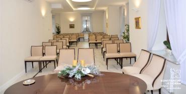 Wnętrze sali ślubów w willi Kamilin. Kremowe ściany, rzędy jasnych krzeseł. 