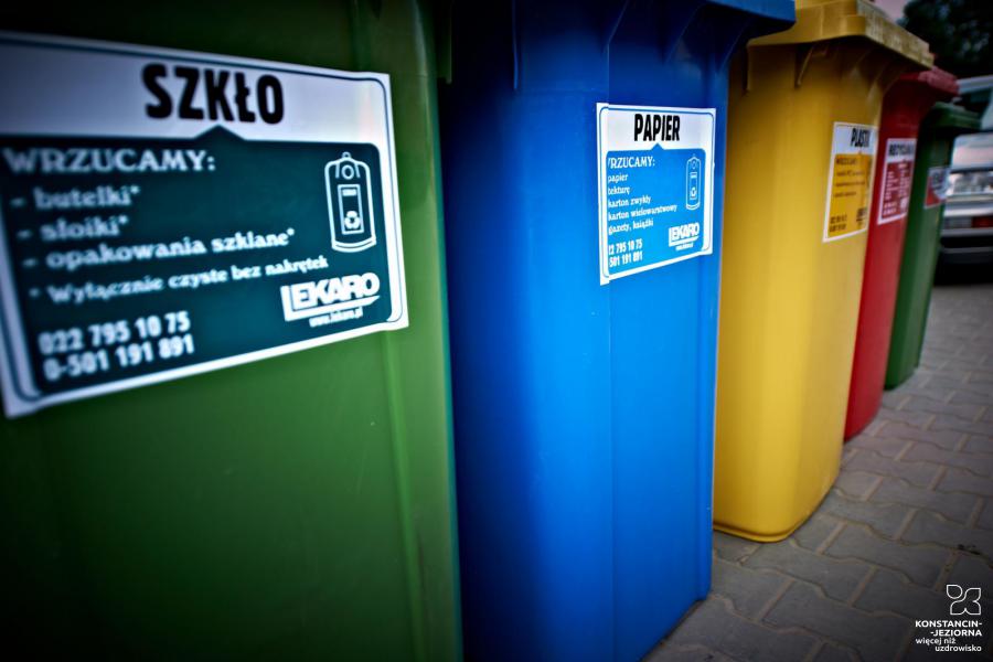 Zdjęcie przedstawia pięć dużych pojemników na śmieci segregowane. Ustawione są obok siebie, różnią się kolorami (od lewej: zielony, niebieski, żółty, czerwony, zielony).