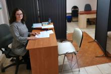 Uśmiechnięta kobieta siedzi przy biurku.