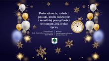 Grafika wektorowa. Na błękitnym tle białe i złote balony, gwiazdy i płatki śniegu. Na środku życzenia od władz gminy, ich treść podana jest w artykule. Poniżej życzeń herb gminy.